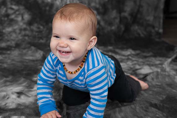 Baby smiles at mom while showing off her crawling skills in this baby portrait by Photos By Orion